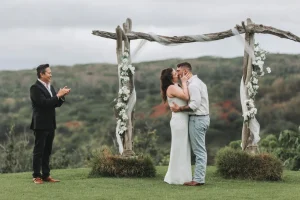 Couple sharing a kiss under a rustic floral arch
