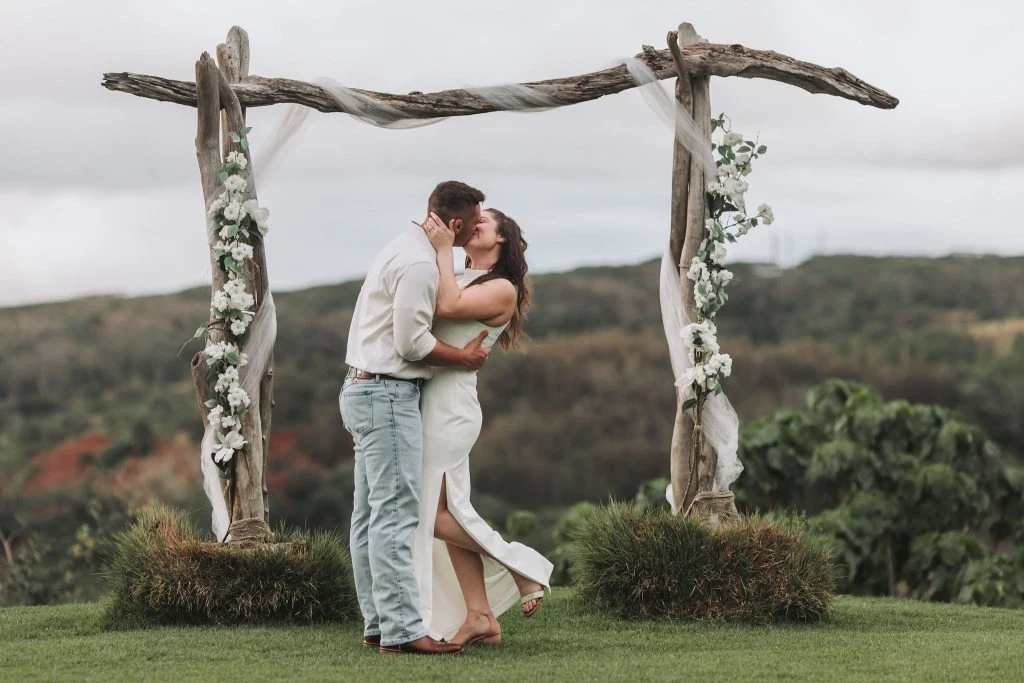 Couple sharing a kiss under a rustic floral arch