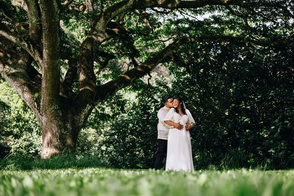 Couple embracing under a large tree