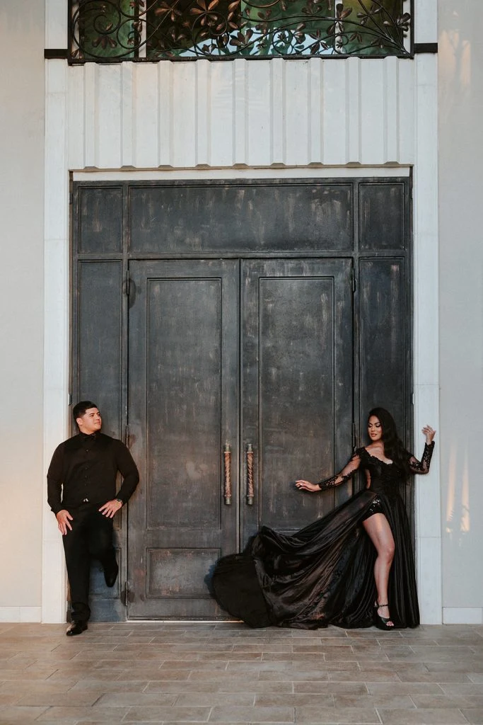 Couple posing in black by a large door