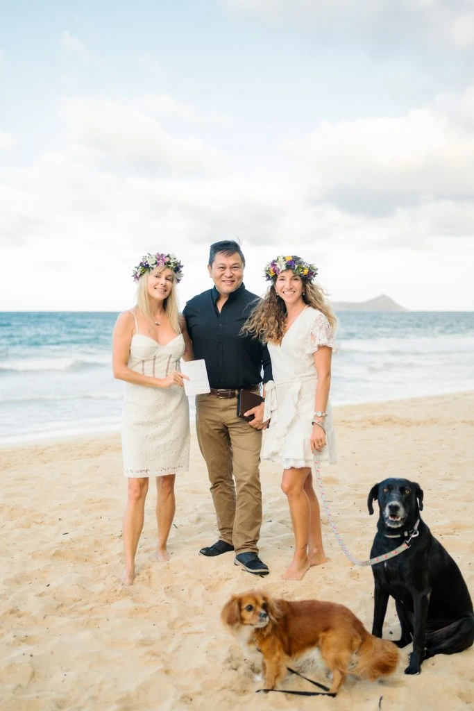Two women with flower crowns and dogs on a beach
