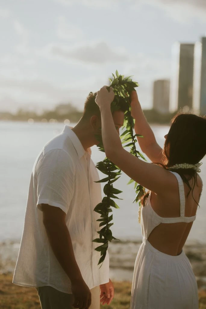 Couple exchanging a lei by the water