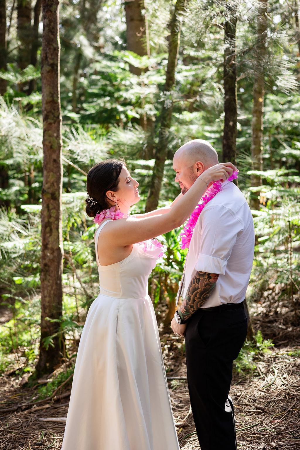 Couple exchanging floral leis during an Oahu beach wedding ceremony.