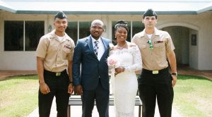 A newly married military couple smiling with two U.S. Navy service members in uniform outside a Honolulu wedding venue on Oahu.