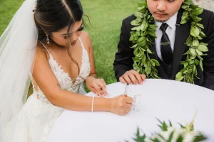 Couple discovering how to get a Hawaii marriage license on Oahu signing official paperwork with their officiant.